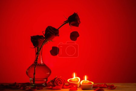 Photo for Silhouette of roses in vase with burning candles on red background - Royalty Free Image