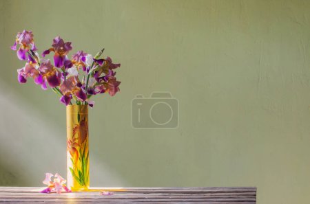 Foto de Iris en hermoso jarrón de vidrio contra la pared verde - Imagen libre de derechos