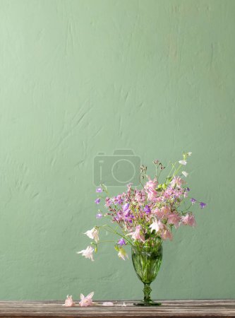 Téléchargez les photos : Fleurs sauvages en bocal vert sur fond mur vert - en image libre de droit