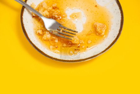 Foto de Plato sucio con miel y migas de pastel sobre fondo amarillo - Imagen libre de derechos