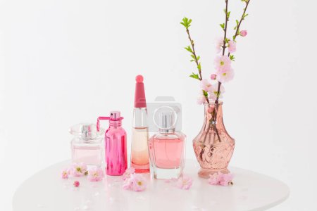 Photo for Branches of blossoming almonds in  vase and perfumes on  white background - Royalty Free Image