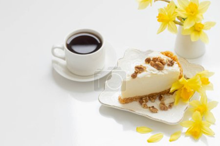 Téléchargez les photos : Gâteau au fromage avec tasse de café et fleurs jaunes de printemps sur table blanche - en image libre de droit