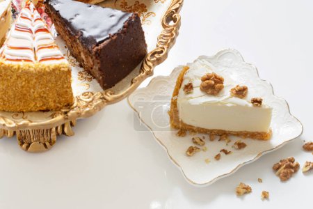Foto de Diferentes pedazos de pastel en plato vintage de oro en la mesa blanca - Imagen libre de derechos
