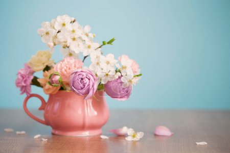Beautiful spring flowers in vintage cup in pastel colors on blue background