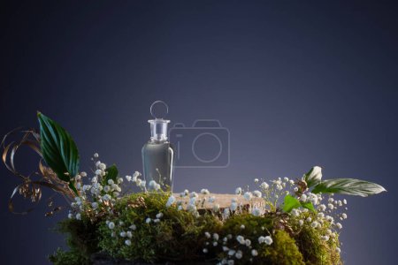 Foto de Poción mágica en botella de vidrio con plantas y flores sobre fondo azul - Imagen libre de derechos