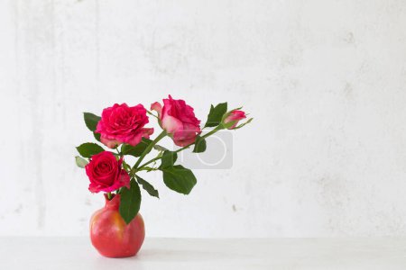 Foto de Rosas rosadas en jarrón rosa sobre fondo pared blanca vieja - Imagen libre de derechos