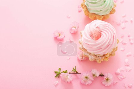 Foto de Cupcakes de color rosa y verde con flores de primavera sobre fondo rosa - Imagen libre de derechos