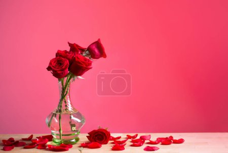 Foto de Rosas rojas en jarrón de vidrio sobre fondo rojo - Imagen libre de derechos