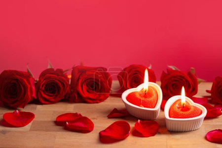Foto de Rosas rojas con velas encendidas sobre fondo rojo - Imagen libre de derechos