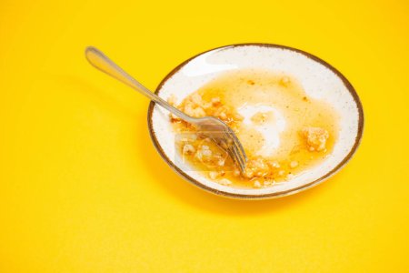 Foto de Plato sucio con miel y migas de pastel sobre fondo amarillo - Imagen libre de derechos