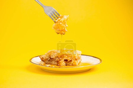 Téléchargez les photos : Gâteau avec du miel sur assiette sur fond jaune - en image libre de droit