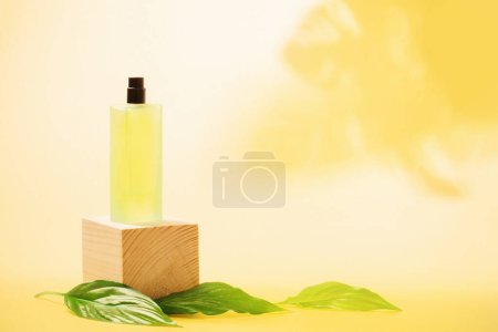 Photo for Perfume bottle with green leaves on yellow background - Royalty Free Image