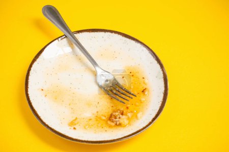 Téléchargez les photos : Assiette sale avec du miel et des miettes de tarte sur fond jaune - en image libre de droit