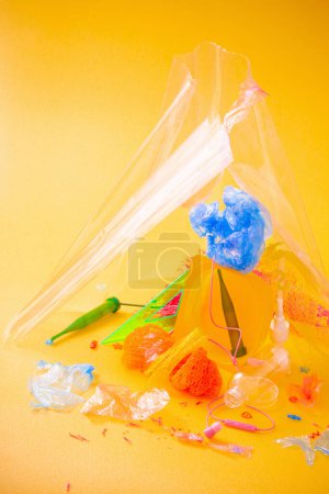 Foto de Basura de plástico sobre fondo amarillo brillante - Imagen libre de derechos