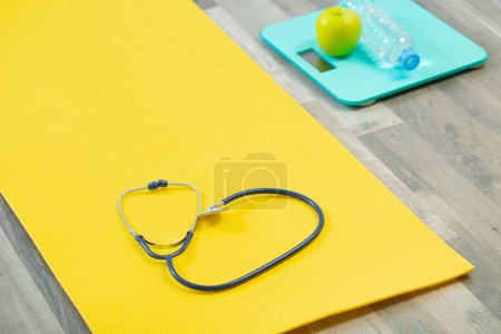 Téléchargez les photos : Stéthoscope sur tapis de fitness, concept de santé cardiaque - en image libre de droit