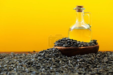 Photo for Oil and sunflower seeds on  wooden table on  yellow background - Royalty Free Image