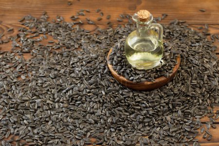 Photo for Oil in glass bottle and sunflower seeds on a wooden table - Royalty Free Image