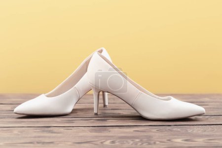 Photo for Beige shoes on wooden floor on yellow background - Royalty Free Image