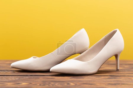 Téléchargez les photos : Chaussures beige sur sol en bois sur fond jaune - en image libre de droit