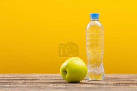 Photo for Bottle of water with green apple on wooden table - Royalty Free Image