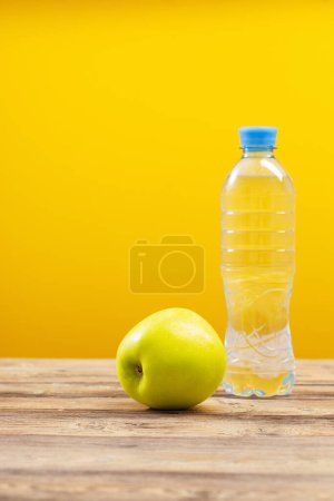 Foto de Botella de agua con manzana verde sobre mesa de madera - Imagen libre de derechos