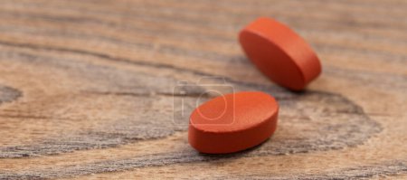 Photo for Two pills on old wooden background - Royalty Free Image