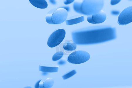 Photo for Flying blue pills on blue background - Royalty Free Image
