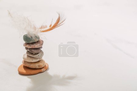 Téléchargez les photos : Cairn avec plume d'oiseau sur fond blanc - en image libre de droit