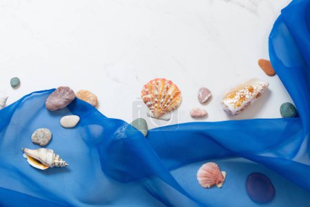 Foto de Fondo marino con tela azul, piedras, conchas marinas sobre mármol blanco - Imagen libre de derechos