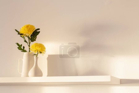 Téléchargez les photos : Chrysanthème jaune dans un vase sur étagère blanche sur fond blanc - en image libre de droit