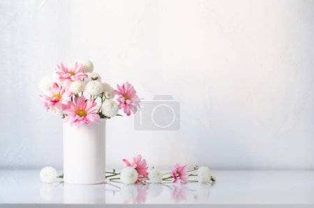 Téléchargez les photos : Chrysanthèmes blancs et roses dans un vase sur fond blanc - en image libre de droit