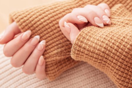 Foto de Las manos de las mujeres con manicura con manta de punto - Imagen libre de derechos