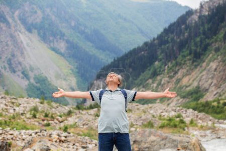 Téléchargez les photos : Heureux homme d'âge moyen avec les bras tendus sur fond de montagnes - en image libre de droit