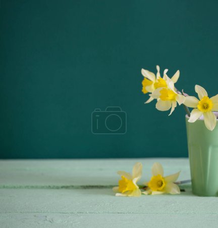 Photo for Yellow narcissus in vase on green background - Royalty Free Image