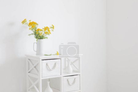 Foto de Amarillo salvaje verano flores en jarra en blanco vintage interior - Imagen libre de derechos