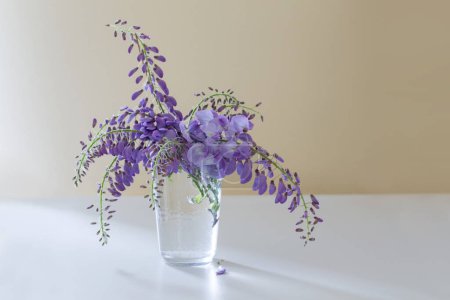 Téléchargez les photos : Fleurs de glycine dans un vase en verre intérieur - en image libre de droit