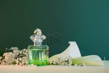 Téléchargez les photos : Bouteille de parfum avec des plantes et des fleurs sur fond vert - en image libre de droit