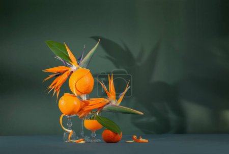 Foto de Naturaleza muerta exótica con flores de pájaro del paraíso, jugo de naranja y frutas de naranja - Imagen libre de derechos