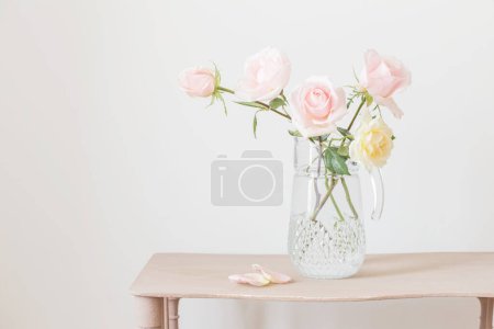 Foto de Hermosas rosas en jarra de vidrio sobre fondo blanco - Imagen libre de derechos