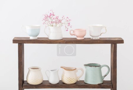 Photo for Pink gypsophila and cups on  wooden shelf on  white background - Royalty Free Image