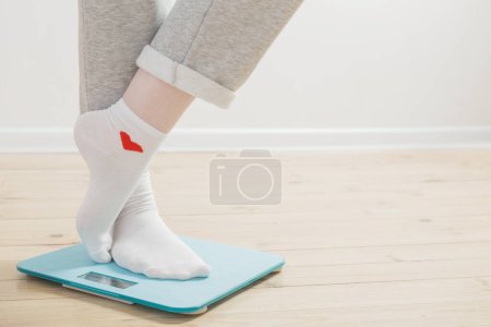 Photo for Female legs on electronic scales on a wooden floor - Royalty Free Image