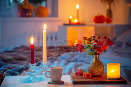 Photo for Cup of tea and  chrysanthemum in vase with burning candles in bedroom - Royalty Free Image