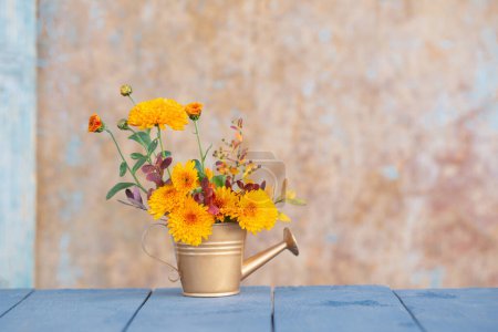 Téléchargez les photos : Fleurs de chrysanthème en arrosoir doré sur fond vieux mur - en image libre de droit