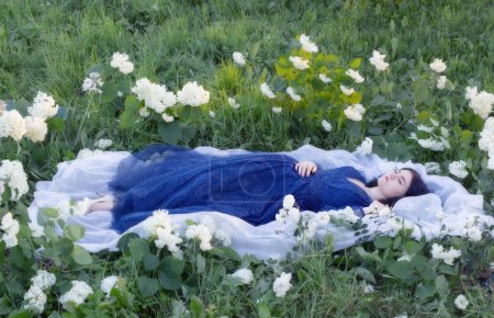 Foto de Joven hermosa mujer en vestido azul en la hierba con flores blancas - Imagen libre de derechos