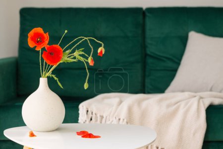 Photo for Red poppies in vase in modern cozy interior with green coach - Royalty Free Image