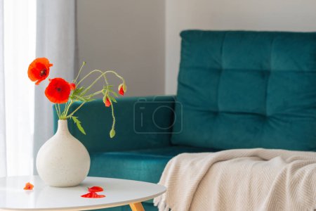 Téléchargez les photos : Coquelicots rouges dans un vase à l'intérieur confortable moderne avec entraîneur bleu - en image libre de droit