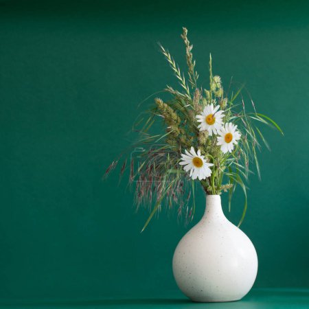 Photo for Wild flowers  in modern vase on green background - Royalty Free Image