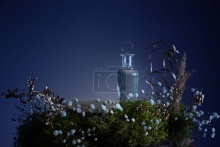Foto de Poción mágica en botella de vidrio con plantas y flores sobre fondo azul - Imagen libre de derechos