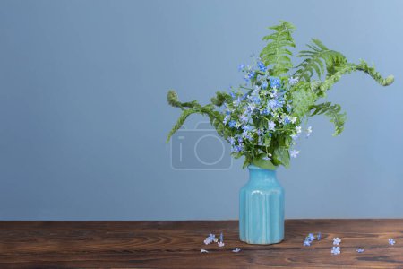 Photo for Wild flowers in vase on background blue wall - Royalty Free Image