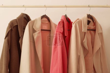 Photo for Female autumn clothes on hangers  in  white room - Royalty Free Image